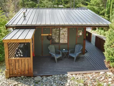a cabin with two chairs and a table on a deck at The Rocky Knoll - Garden View - Pet Friendly in Port Renfrew
