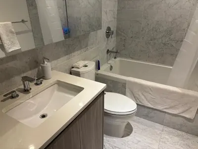 a bathroom with a sink and a toilet and a tub at Sleek Urban 1BR Retreat in Burnaby