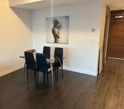 a dining room with a table and chairs and a painting at Sleek Urban 1BR Retreat in Burnaby