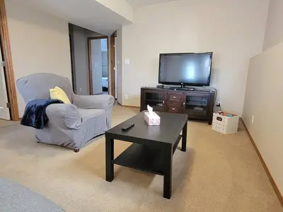 a living room with a tv and a chair and a coffee table at Quaint Lonsdale Suite in Red Deer