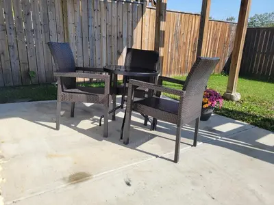 three chairs and a table on a patio at Quaint Lonsdale Suite in Red Deer