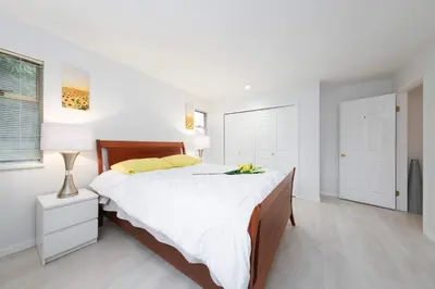a white bedroom with a large bed with yellow pillows at Private Room with Full Amenities in Cozy House in Vancouver