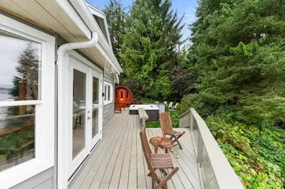 a porch with two chairs and a grill on a house at Hot tub - Sauna - Panoramic Ocean View THE POINT - Pet Friendly in Port Renfrew