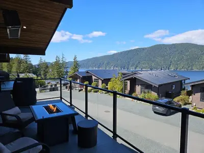 a balcony with a view of a lake and mountains at Oceanview - Pet Friendly - Gas Fireplace - Wild Beauty in Port Renfrew