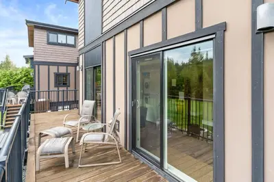 a balcony with two chairs and a sliding glass door at Oceanview - Pet Friendly - Gas Fireplace - Wild Beauty in Port Renfrew