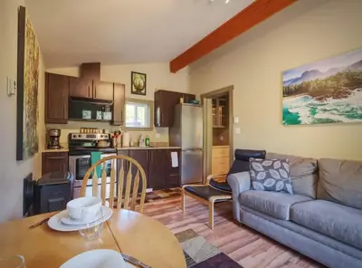 a kitchen and a living room with a couch and a table at Explorers Retreat Private Sauna - Pet Friendly in Port Renfrew