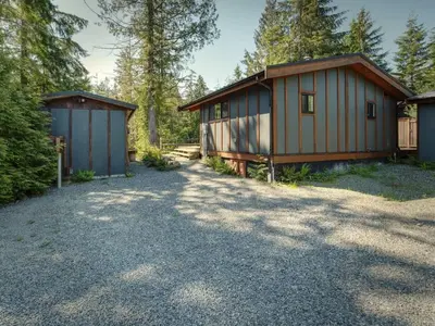 a couple of buildings sitting in the woods at Explorers Retreat Private Sauna - Pet Friendly in Port Renfrew