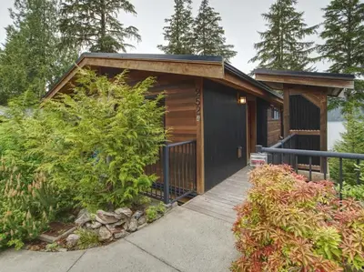 a small cabin with a wooden walkway in a garden at Going Coastal A - Oceanfront - Pet Friendly in Port Renfrew