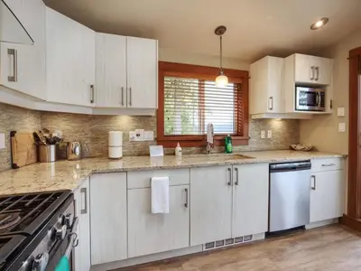 a kitchen with white cabinets and a stove top oven at Going Coastal A - Oceanfront - Pet Friendly in Port Renfrew