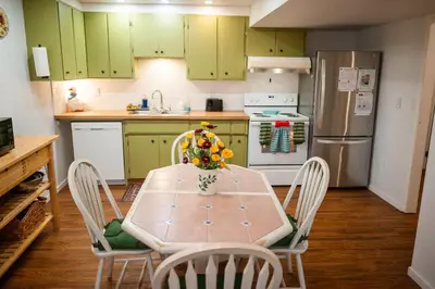 a kitchen with green cabinets and a table and chairs at Spacious 2-Bedroom Basement Suite in Whitehorn, Close to Calgary Airport, Hospital, & Train in Calgary