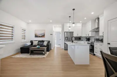 a kitchen and living room with a couch and a table at NEW Family 3BR Upper Suite w Kid's Play Den, Free Banff Pass in Calgary