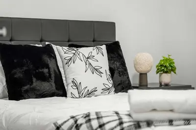 a bed with black and white pillows on it at Large 5BR Family Home w Kids Play Den & Private Basement Suite Included, FREE Banff Pass! in Calgary