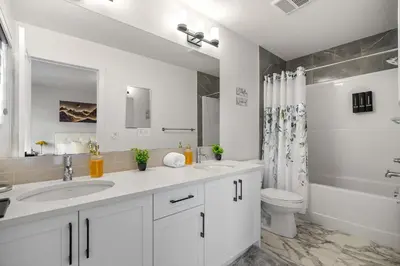 a white bathroom with a sink and a toilet at Large 5BR Family Home w Kids Play Den & Private Basement Suite Included, FREE Banff Pass! in Calgary