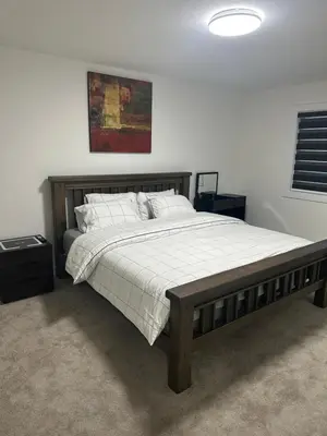 a bedroom with a large bed with a wooden frame at Brand New 3 Bedroom house SW Edmonton in Edmonton