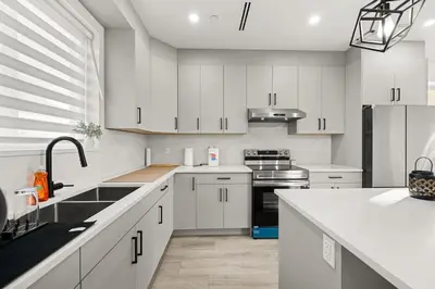 a kitchen with white cabinets and a sink at Bright Modern 3 Bedroom Suite in Vancouver in Vancouver