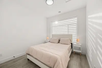a white bedroom with a bed and a window at Bright Modern 3 Bedroom Suite in Vancouver in Vancouver