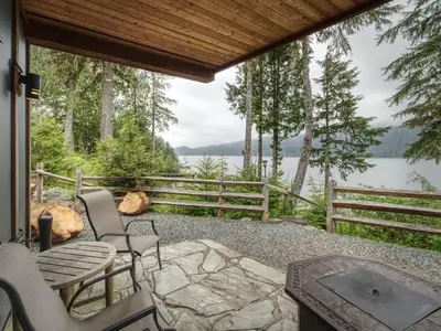 a patio with chairs and a view of a lake at Going Coastal ABC - Oceanfront - Pet Friendly in Port Renfrew