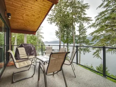 a patio with chairs and a table and a view of the water at Going Coastal AB - Oceanfront - Pet Friendly in Port Renfrew