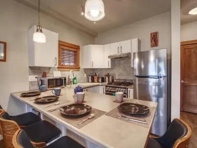 a kitchen with a counter with chairs and a refrigerator at Going Coastal AB - Oceanfront - Pet Friendly in Port Renfrew