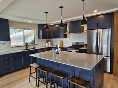 a kitchen with blue cabinets and a large island with bar stools at Hot Tub - Sleep 12 - EV Charger J1772 - Forest View - Pet Friendly in Mount Washington