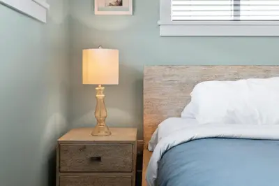 a bedroom with a bed and a lamp on a night stand at Spacious Oceanview - 2 living rooms & fridges - Pet Friendly in Port Renfrew