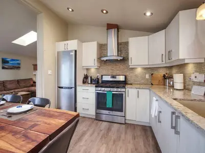 a kitchen with white cabinets and a stainless steel refrigerator at Oceanfront view - Pet Friendly - Sleep 8 in Port Renfrew