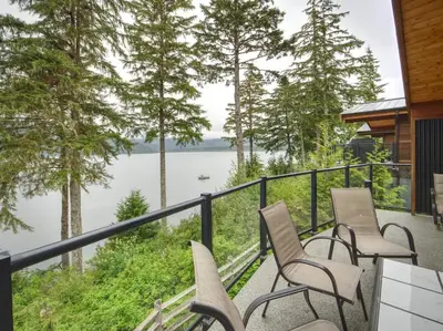 a balcony with chairs and a view of a lake at Oceanfront view - Pet Friendly - Sleep 8 in Port Renfrew