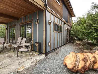 a porch of a house with chairs and a log at Oceanfront view - Pet Friendly - Sleep 8 in Port Renfrew