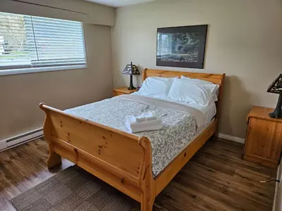a bedroom with a wooden bed with white pillows at The Outfitter - Garden View - Pet Friendly - Huge yard in Port Renfrew