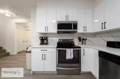 a kitchen with white cabinets and a stove and microwave at Spacious Private Apartment with King Bed, Full Kitchen and In-Suite Laundry in Edmonton