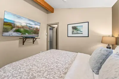 a bedroom with a bed and a tv on the wall at JDF Waystation Cabin - Garden View - Pet Friendly in Port Renfrew