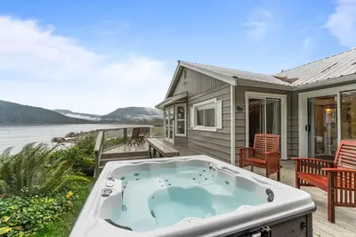 a hot tub on a deck next to a house at The Point Partial - Hot tub - Sauna - view of San Juan Bay - Pet Friendly in Port Renfrew