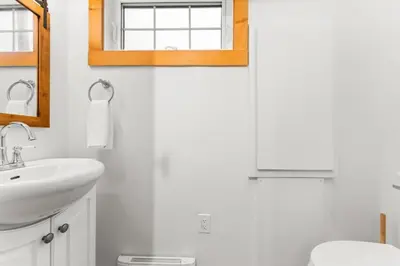 a white bathroom with a sink and a mirror at The Point Partial - Hot tub - Sauna - view of San Juan Bay - Pet Friendly in Port Renfrew