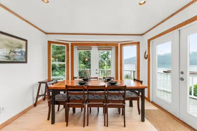a dining room with a table and chairs and windows at The Point Partial - Hot tub - Sauna - view of San Juan Bay - Pet Friendly in Port Renfrew