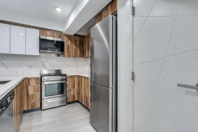 a kitchen with a stainless steel refrigerator and wooden cabinets at Prime West End 2BR- Central Vancouver Lifestyle in Vancouver