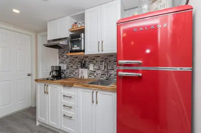 a red refrigerator in a kitchen with white cabinets at 2 Bedroom 1 Bath On An Oak Tree Lined End Street On The Galloping Goose in Victoria