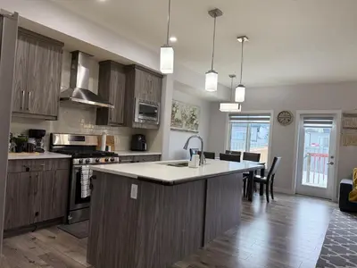 a kitchen with wooden cabinets and a large island in the middle at Family Friendly GarageFireplace Sleeps 8 in Edmonton