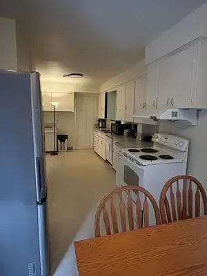 a kitchen with white appliances and a table and chairs at Vancouver Budget Stay - Airport 10 Min - Free Parking & Fast WiFi in Vancouver