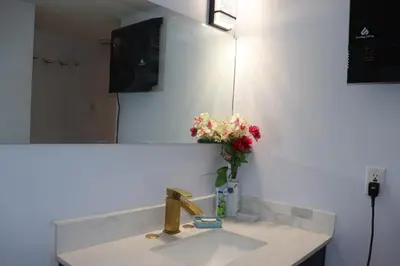 a bathroom sink with a vase of flowers on it at Cozy home in Calgary