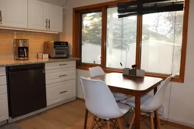 a kitchen with a wooden table and white chairs at Cozy home in Calgary