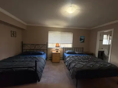 a bedroom with two beds and a lamp and a window at North Delta Budget Stay - Scott Road - Free Parking & Fast WiFi in Delta