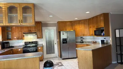a kitchen with wooden cabinets and a stainless steel refrigerator at North Delta Budget Stay - Scott Road - Free Parking & Fast WiFi in Delta