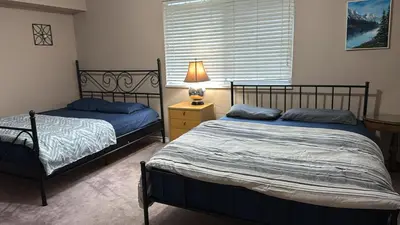 a bedroom with two beds and a lamp and a window at Budget Stay Near Scott Road - Transit, Free Parking & Fast WiFi in Delta