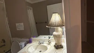 a lamp sitting on a bathroom sink in front of a mirror at Budget Stay Near Scott Road - Transit, Free Parking & Fast WiFi in Delta