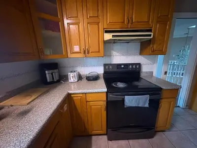 a kitchen with wooden cabinets and a black stove at Budget Stay Near Scott Road - Transit, Free Parking & Fast WiFi in Delta