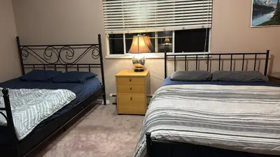 a bedroom with two beds and a lamp on a night stand at Budget Stay Near Scott Road - Transit, Free Parking & Fast WiFi in Delta