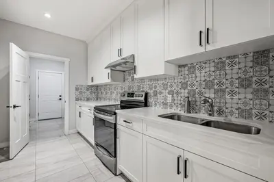 a kitchen with white cabinets and a stainless steel sink at Spacious 8 Bedroom Family Retreat in Calgary