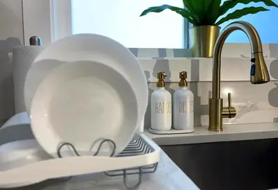 a white plate sitting on a counter next to a sink at Ocean-Inspired Art Suite in Langford