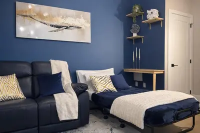 a blue living room with a couch and a ottoman at Ocean-Inspired Art Suite in Langford