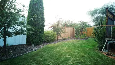 a backyard with a fence and a grass yard at Spacious 3BR Retreat w-Hot Tub Ravine Sleeps 9 in Edmonton